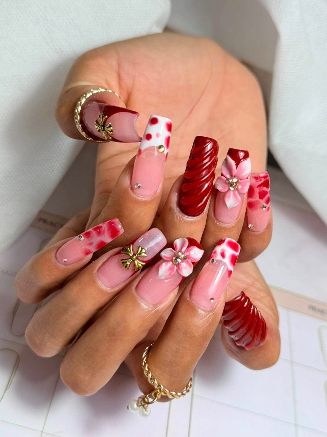 Nail art i rosa og dyb rød med håndmalede detaljer